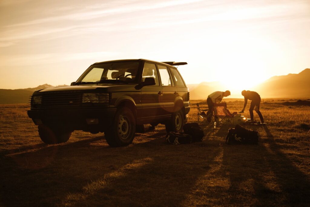 Two people camping next to a jeep